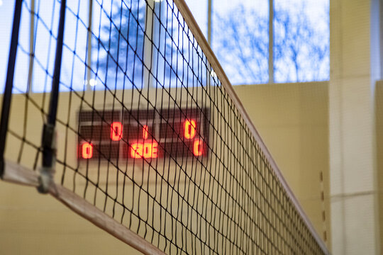 Net of volleyball court in old school gym at scoreboard background. Sports image of volleyball net in sport hall. Concept of team game, active match, healthy lifestyle and team success. Copy space