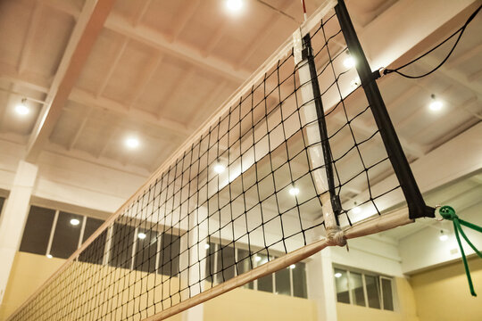 Net of volleyball court in old school gym, bottom view. Background sports image of volleyball net in sport hall. Concept of team game, active match, healthy lifestyle and team success. Copy space