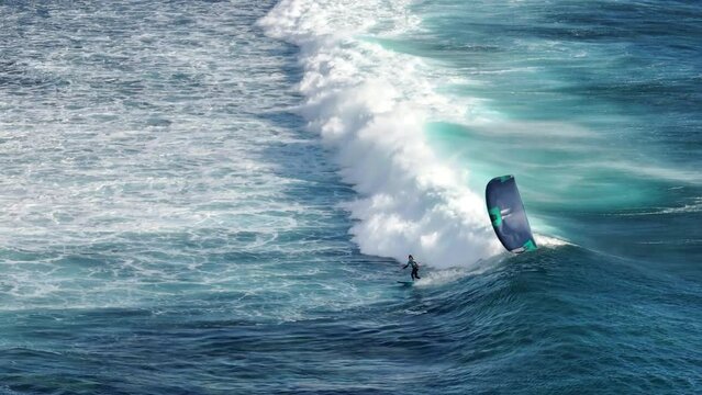 An athlete rides a kite on big waves in the Indian Ocean on the island of Mauritius. Big ocean waves on a live reef. Conquest of the sea