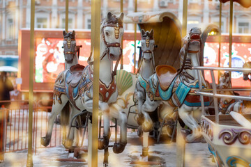 Fototapeta na wymiar Traditional fair carousel with horses. An old French carousel in a leisure park in diffuse yellow lights.