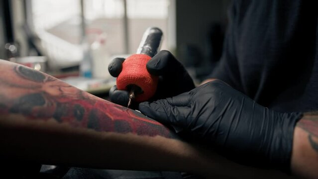 Close-up - the process of tattooing a woman on her leg. Male tattoo artist making a tattoo