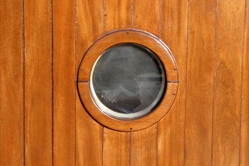 Cute round window, oeil-de-boeuf, polished light brown wood from a restored old ship.