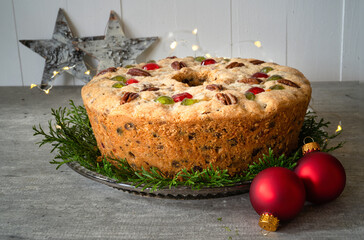 Homemade  light fruitcake decorated with cedar boughs and Christmas baubles. - obrazy, fototapety, plakaty