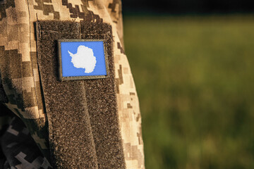 Close up millitary woman or man shoulder arm sleeve with Antarctica flag patch. Antarctica troops army, soldier camouflage uniform. Armed Forces, empty copy space for text
