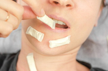 A woman puts a packet of Swedish snus into her mouth. Swedish snus