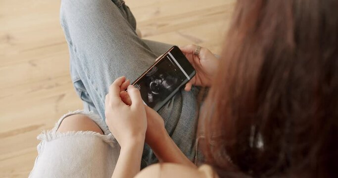 Two women looking at ultrasound image of future baby on smartphone. Embrace and holding each other. Two women sharing love and support holding hands. Lifestyle and relationships. LGBT concept