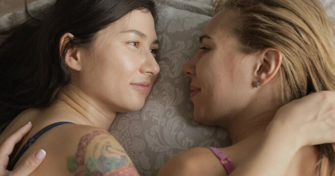 the view from the top two cozy and cute lesbians lie in the bedroom on the bed and caress each other. LGBT