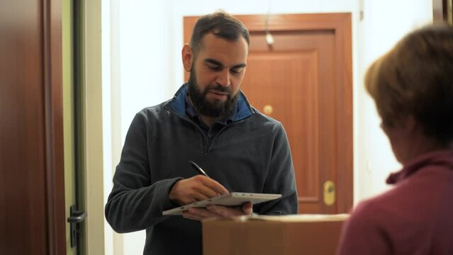 Bearded man delivering a package. Holding a parcel in front of the door. 