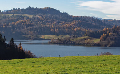 Contrast of green grass with autumn mountains at Czorsztyn Lake.