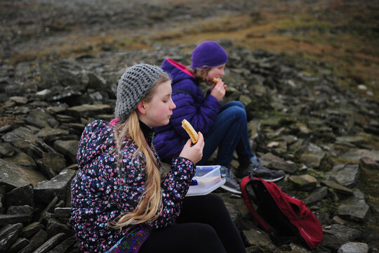 2 girls eat sandwiches on the top of Ingleborough