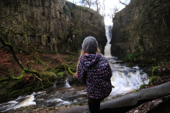 A girl looks at a waterfall in the countryside