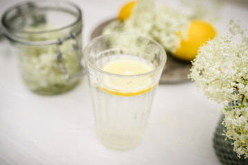 STakan with lemonade with elderberry syrup, Traditional summer refreshing drink. Still life with fresh elderberry flowers and lemons.