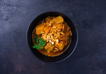 Traditional Indian vegetarian Madras curry stew with sweet potatoes and roasted cashew nuts served as top view in design bowl with copy space
