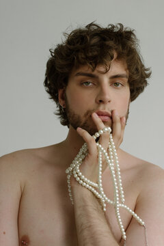 A cute curly-haired guy with pearls and pierced nips
