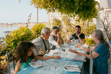 Multigenerational group of people sitting by restaurant terrace table