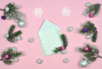 Pink winter background with pine tree branches,  snowballs ,snowflakes ,white blank-card with an embossed pattern .Top view, flat lay..Christmas or New Year greeting concept. Free space for message