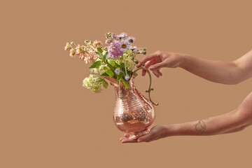 Elegant copper vase with flowers in hands.