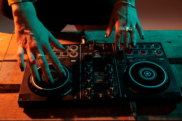 Performer artist mixing sounds at dj turntables, using audio equipment to play music and do musical...