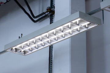 Naklejka premium Close-up of an industrial fluorescent lamp, lamps hanging from the ceiling in a warehouse