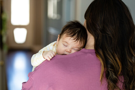 Brunette Woman Holds Baby Over Her Shoulder