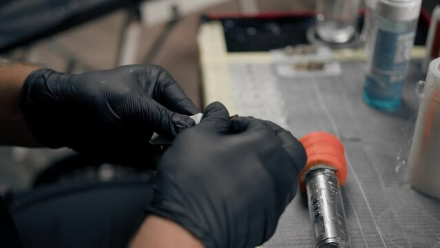 Tattoo artist collects tattoo washing machine. Tattoo needles. Tattoo artist in studio preparing