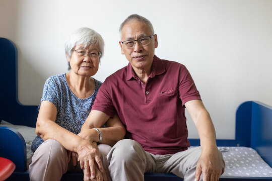 senior old asian couple smiling portrait sitting together at home