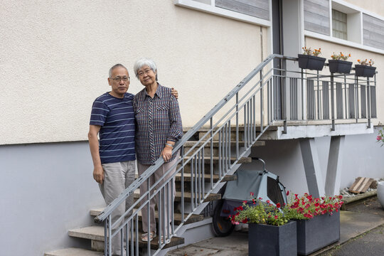 retired couple portrait in front of their house, looking at camera