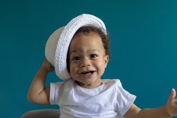 surprised smiling one year old baby portrait in hat, fashion child boy