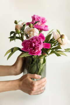 Hands carring glass vase with flowers inside