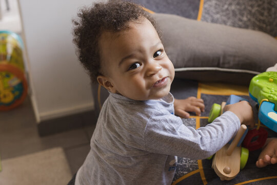 one year old child playing with toys, portrait looking at camera