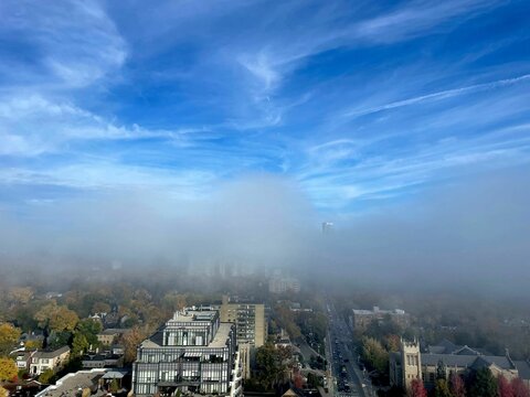 Vertical image of Toronto city covered by smoke on an autumn day with a clear sky above the smoke