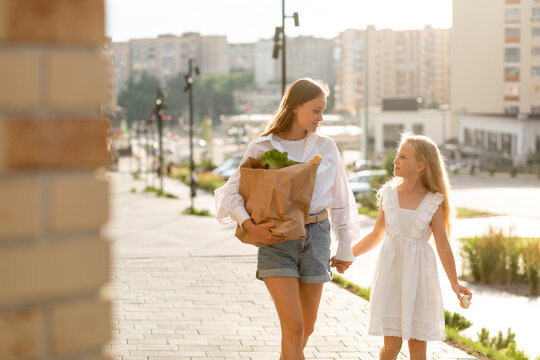 Two sisters walking from shopping center with bags of food