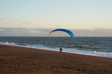 Obraz premium Paraglider walking on the beach, Dorset