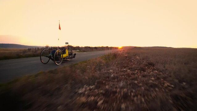 Scenic Shot of a Young Man Athlete with disability Riding a Handcycle. Adaptive Exercise Outdoors at Sunset . High quality 4k footage