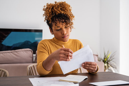Hispanic businesswoman opening letter at home