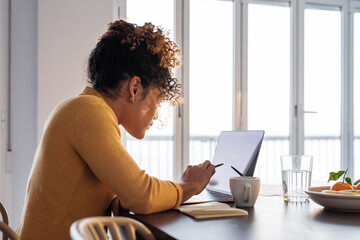 Hispanic businesswoman analyzing data on laptop