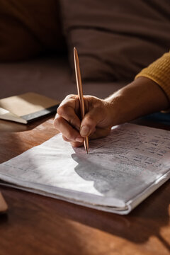 Anonymous freelancer making notes in sunlit living room