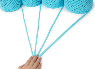 A woman's hand holds several rolls of cotton blue on a white background