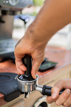 Closeup to a person hands pressing coffee on a tamper