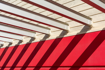 Shadow pattern of pergola steel beams on painted wall on a sunny day