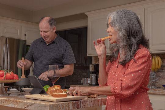 Mature Woman Snacks While Mature Man Cooks