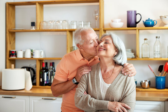 Senior husband kissing wife in kitchen