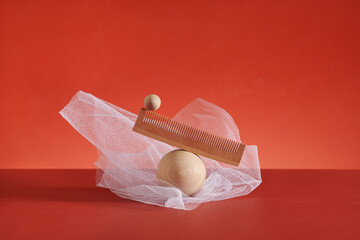 wooden comb balancing on wooden ball on the red background