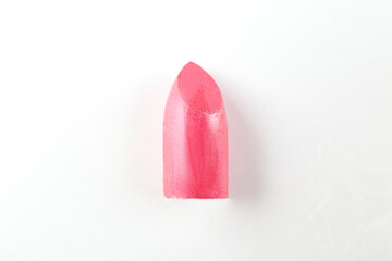 Close up shot of a single glossy lipstick without a tube, isolated on white background with a lot of copy space for text.