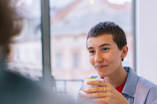 Girl listening person while holding cup of coffee