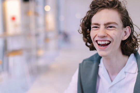 Young Man with Curly Hair Laughing in cafe