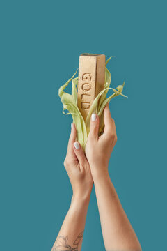 Gold ingot styled as corn cob in woman's hands.