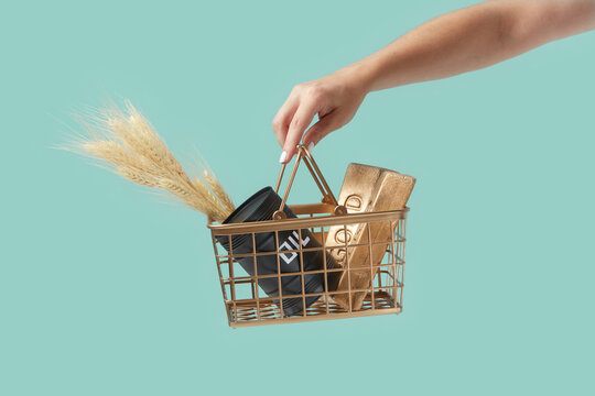 Wheat, oil barrel and gold held by woman's hand.