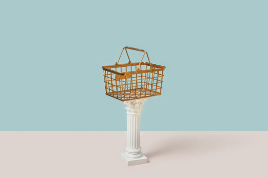 Golden shopping basket on antique white column.