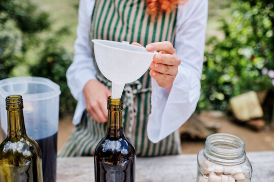 Hands placing a funnel in a wine bottle